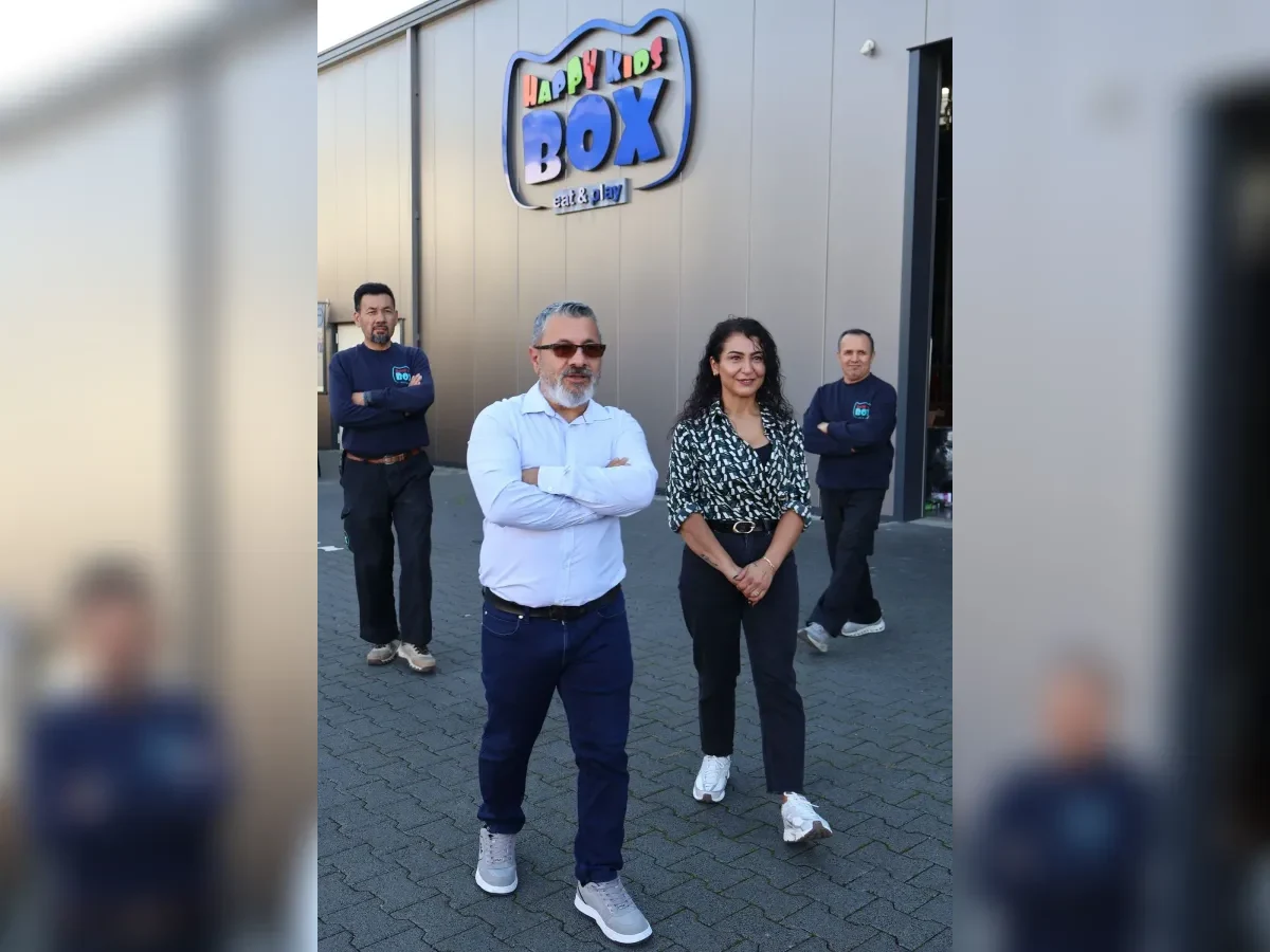 Geschäftsführer Ugur Doganay, seine Ehefrau und zwei Mitarbeiter unter dem 3D-Wandlogo der Happy Kids Box GmbH eat&play